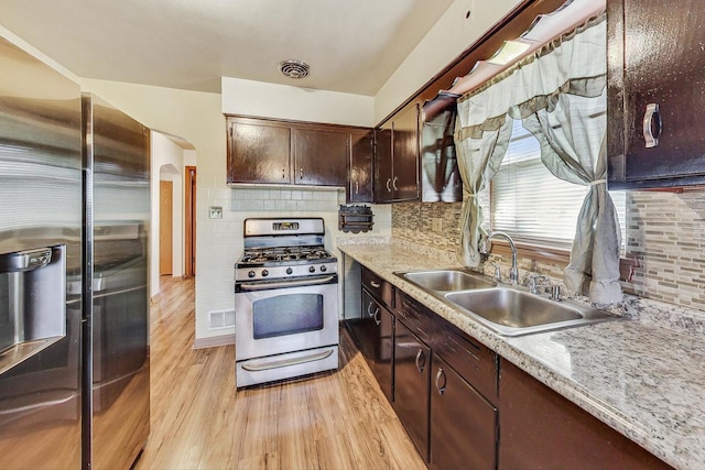 kitchen with sink, light hardwood / wood-style flooring, decorative backsplash, dark brown cabinets, and appliances with stainless steel finishes