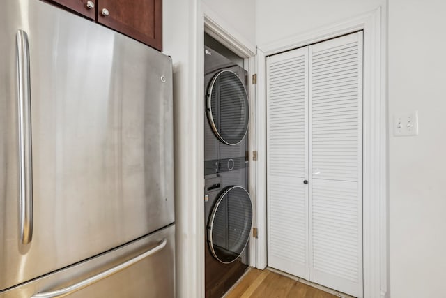 clothes washing area featuring light hardwood / wood-style flooring and stacked washer / drying machine