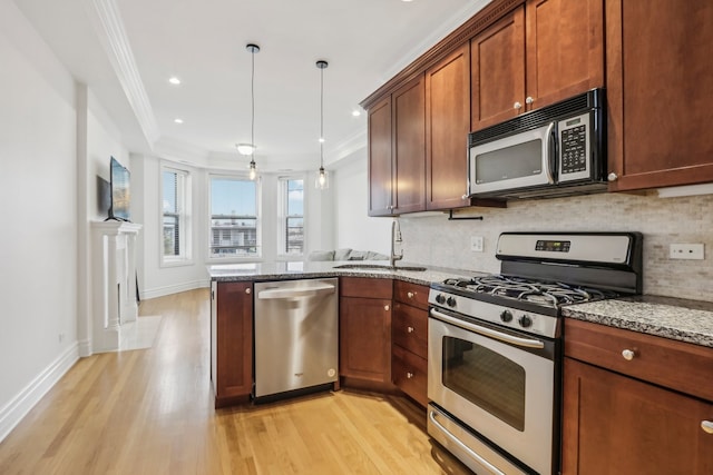 kitchen featuring appliances with stainless steel finishes, sink, stone countertops, decorative light fixtures, and light hardwood / wood-style floors