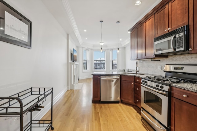 kitchen featuring dark stone counters, sink, light wood-type flooring, appliances with stainless steel finishes, and decorative light fixtures