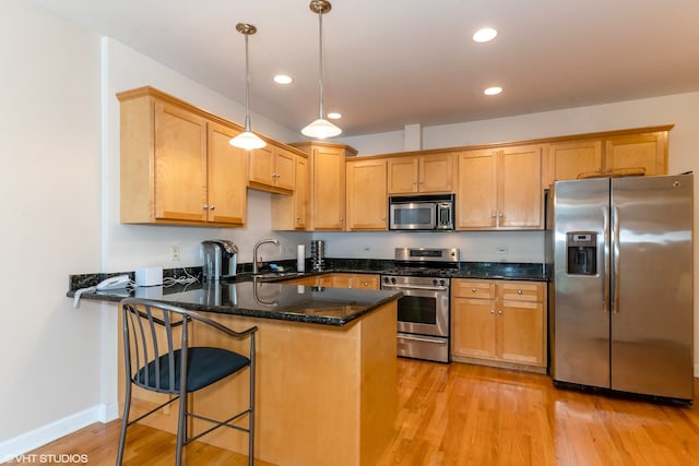 kitchen featuring stainless steel appliances, hanging light fixtures, light hardwood / wood-style flooring, and kitchen peninsula