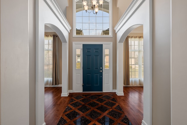 entryway with dark hardwood / wood-style flooring, a towering ceiling, and a chandelier