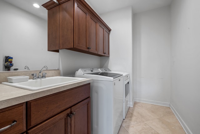 clothes washing area featuring separate washer and dryer, sink, light tile patterned floors, and cabinets