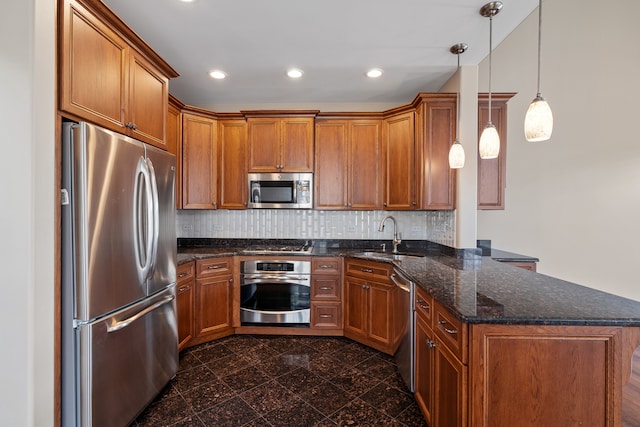 kitchen featuring sink, backsplash, dark stone counters, pendant lighting, and appliances with stainless steel finishes