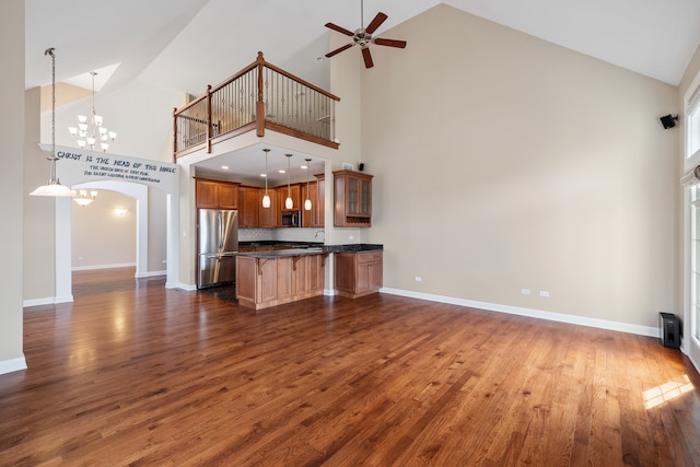 kitchen with high vaulted ceiling, hanging light fixtures, dark hardwood / wood-style flooring, tasteful backsplash, and stainless steel appliances