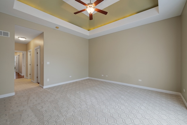 spare room with light carpet, a raised ceiling, and ceiling fan