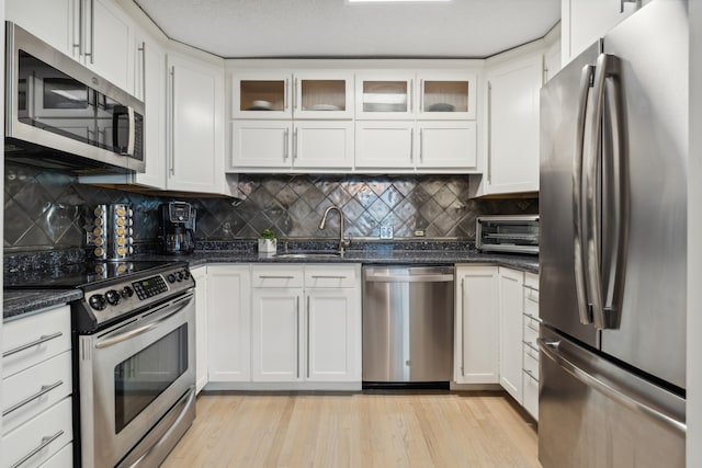 kitchen featuring tasteful backsplash, stainless steel appliances, sink, light hardwood / wood-style flooring, and white cabinetry