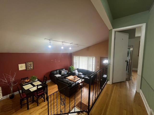 living room with light hardwood / wood-style floors, track lighting, and lofted ceiling