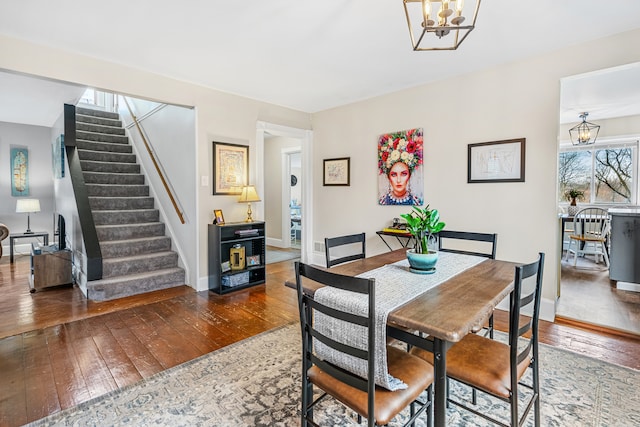 dining space featuring dark wood-type flooring and an inviting chandelier