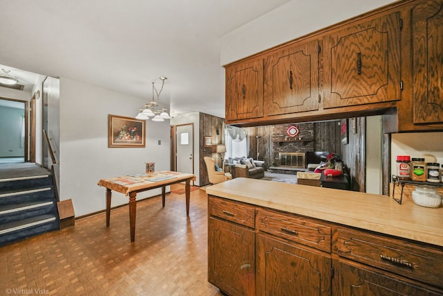 kitchen featuring pendant lighting, a chandelier, and a brick fireplace