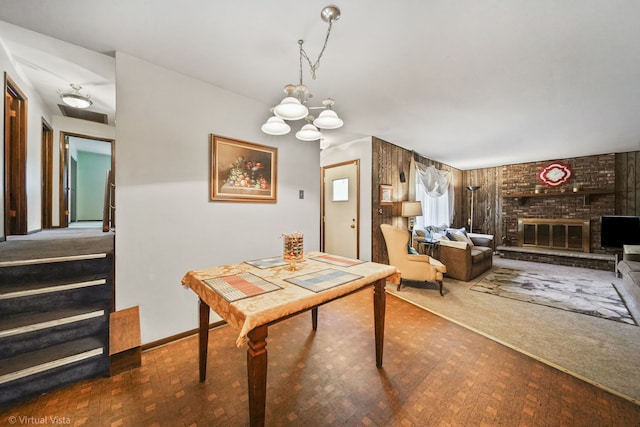 dining space featuring a fireplace, carpet, and a chandelier