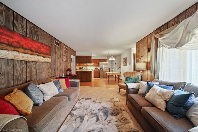 living room featuring wood walls, light wood-type flooring, and a notable chandelier