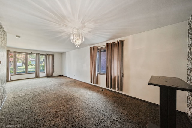 carpeted spare room with a chandelier