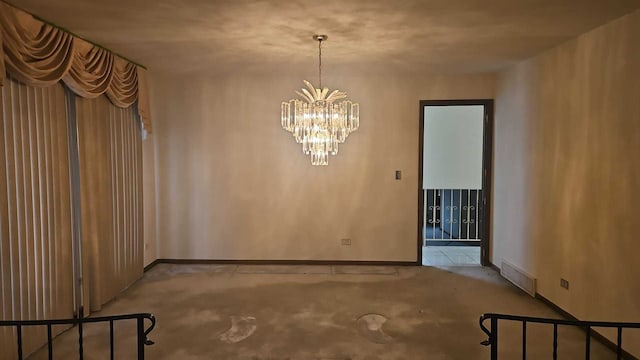 carpeted spare room with a chandelier