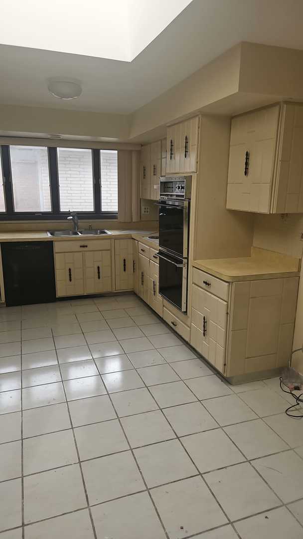 kitchen with light brown cabinetry, sink, light tile patterned floors, and black appliances