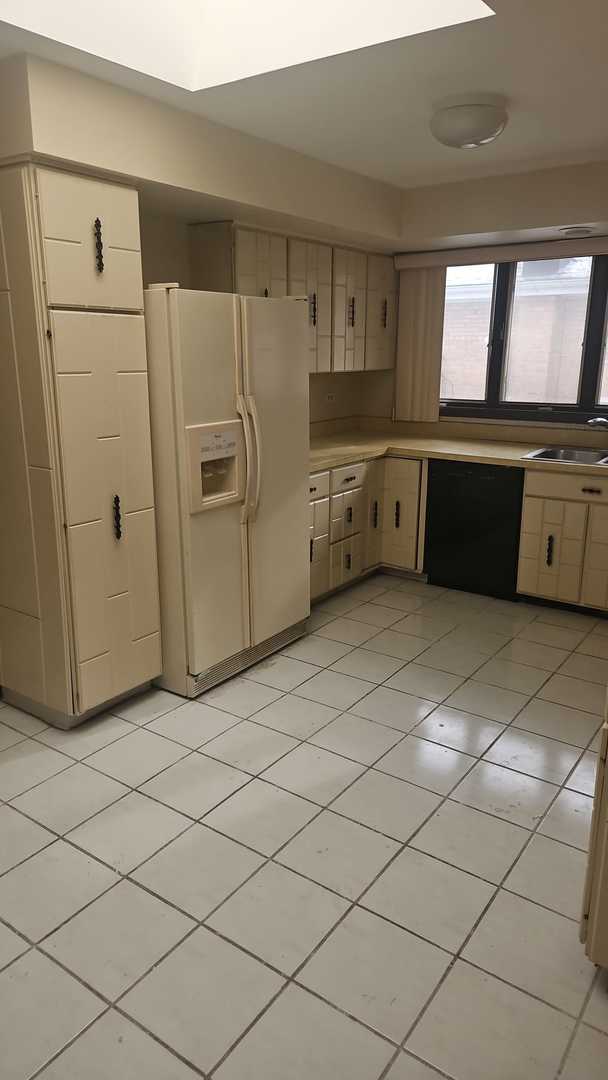 kitchen featuring decorative backsplash, sink, cream cabinetry, black dishwasher, and white fridge with ice dispenser