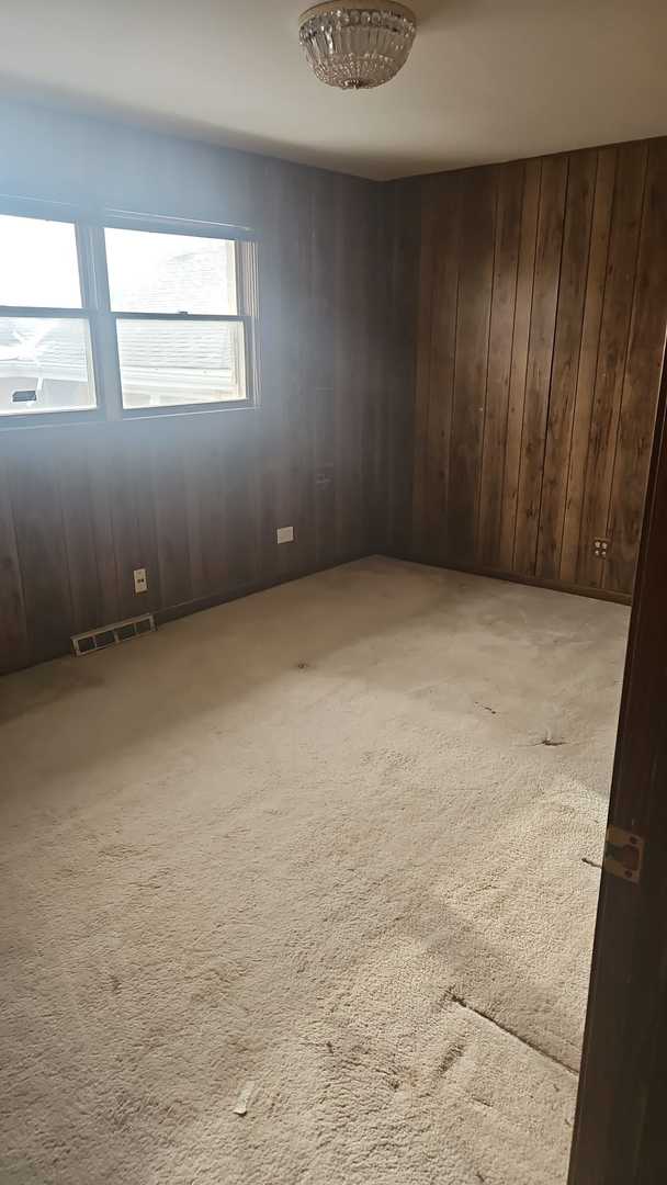 empty room featuring light carpet and wood walls