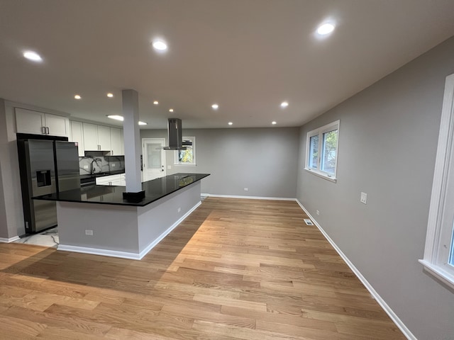 kitchen featuring island range hood, white cabinetry, stainless steel fridge, and light wood-type flooring