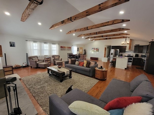 living room with vaulted ceiling with beams, wood-type flooring, and an inviting chandelier