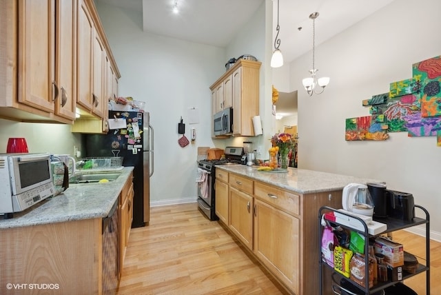 kitchen featuring light hardwood / wood-style floors, light stone countertops, stainless steel appliances, and an inviting chandelier