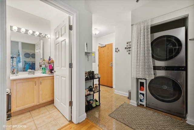 clothes washing area featuring stacked washer and dryer and sink