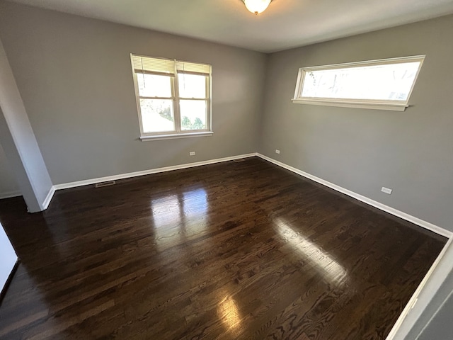 empty room with dark hardwood / wood-style floors and a healthy amount of sunlight