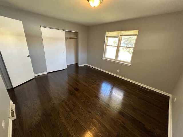 unfurnished bedroom with a closet and dark wood-type flooring