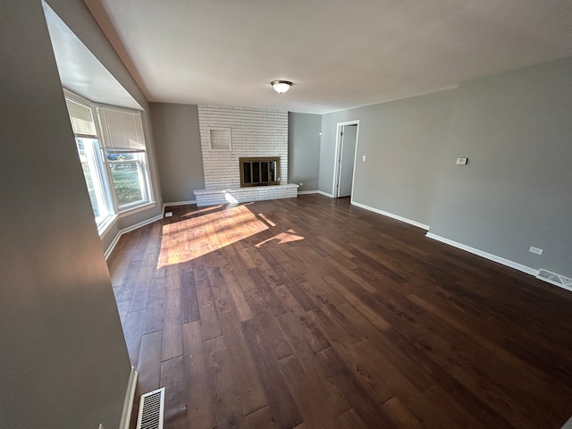 unfurnished living room featuring dark hardwood / wood-style floors and a brick fireplace