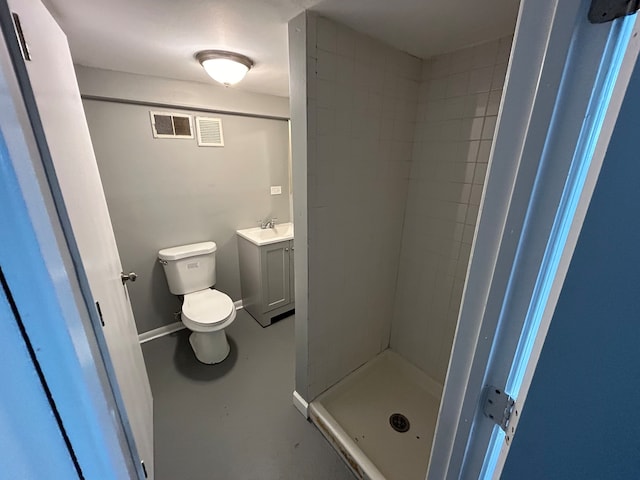 bathroom with concrete floors, vanity, toilet, and tiled shower