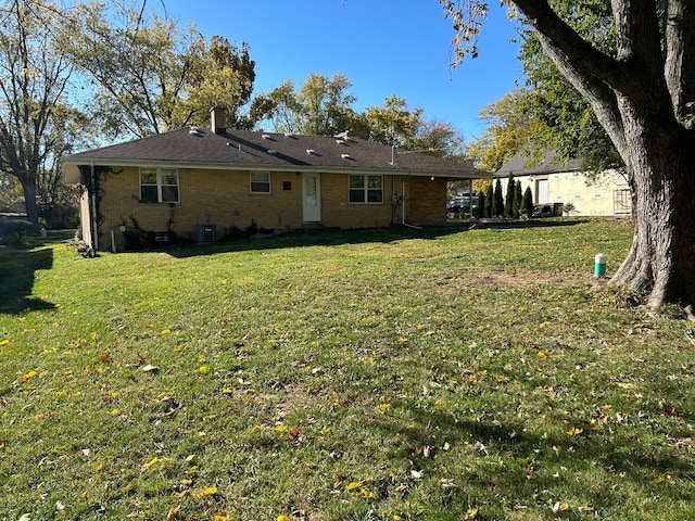 rear view of property with a yard and central air condition unit