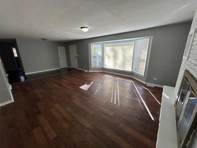 unfurnished living room with dark hardwood / wood-style floors and a brick fireplace