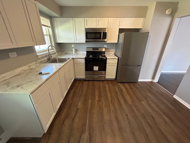 kitchen with light stone countertops, stainless steel appliances, dark wood-type flooring, sink, and white cabinetry