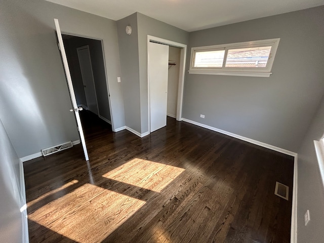 unfurnished bedroom featuring a closet and dark wood-type flooring