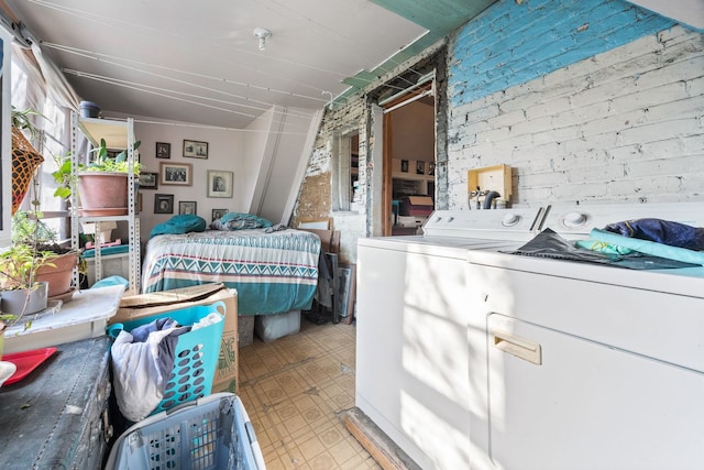 bedroom with separate washer and dryer and brick wall