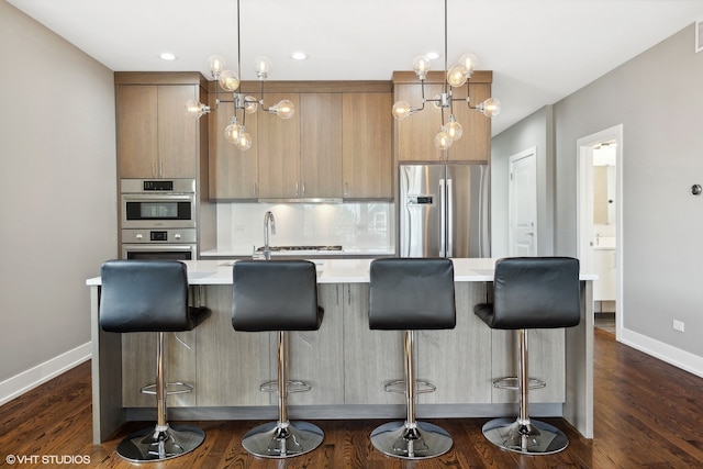 kitchen featuring a kitchen bar, appliances with stainless steel finishes, and dark wood-type flooring