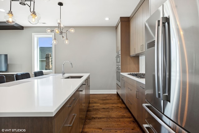 kitchen featuring pendant lighting, dark hardwood / wood-style flooring, stainless steel appliances, and sink