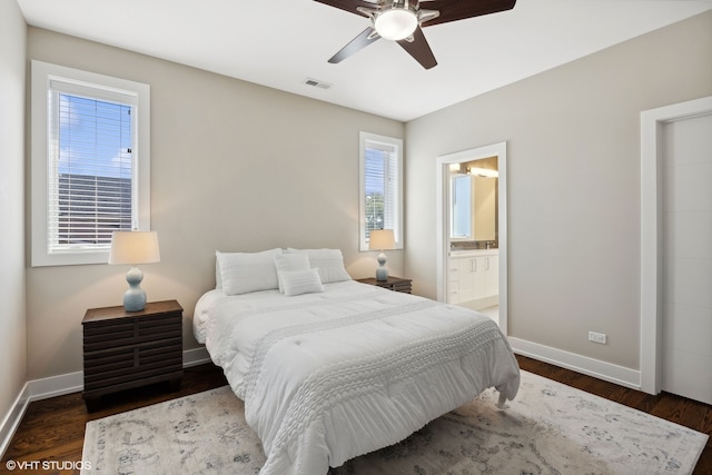 bedroom featuring connected bathroom, multiple windows, and dark wood-type flooring