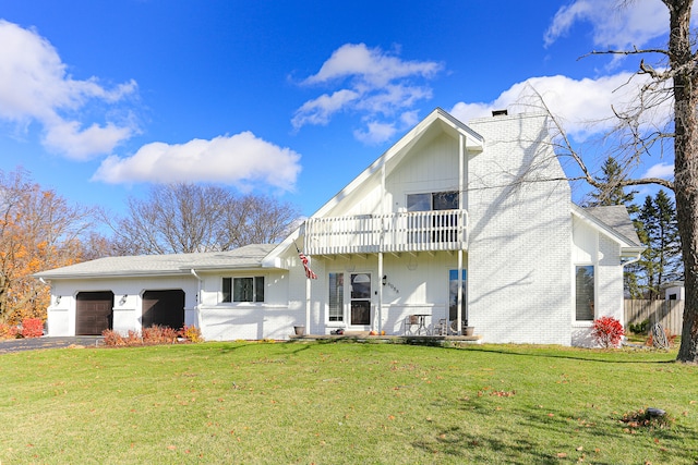 rear view of property featuring a yard, a balcony, and a garage