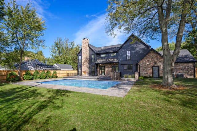 rear view of house with a yard, a fenced in pool, and a patio area