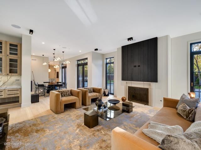 living room with a large fireplace and light wood-type flooring