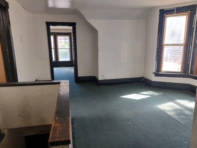 additional living space featuring dark colored carpet, lofted ceiling, and a wealth of natural light