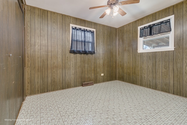 unfurnished room with ceiling fan and wooden walls