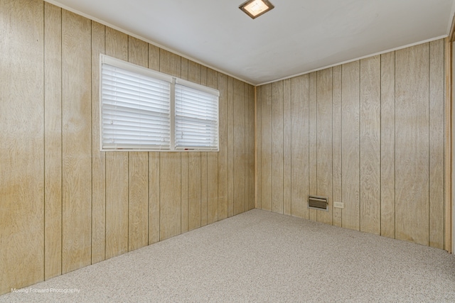 carpeted empty room featuring wooden walls