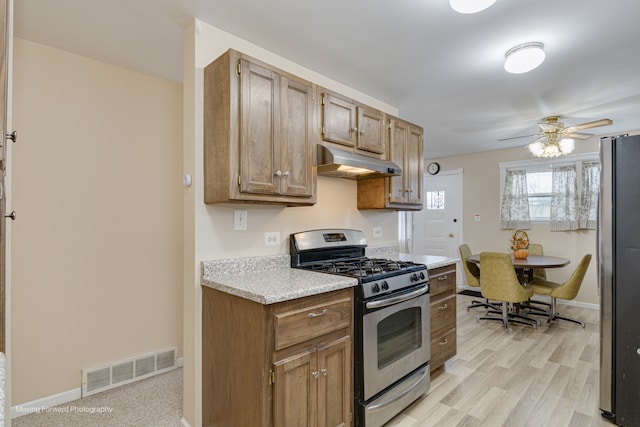 kitchen with appliances with stainless steel finishes, light hardwood / wood-style flooring, and ceiling fan