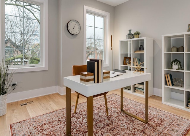 office area featuring visible vents, plenty of natural light, baseboards, and wood finished floors