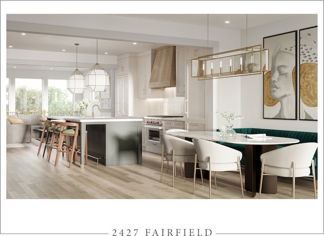 kitchen featuring backsplash, pendant lighting, high end stove, an island with sink, and custom range hood