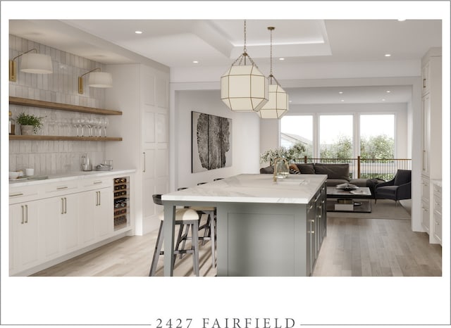 kitchen featuring decorative light fixtures, wine cooler, a center island, white cabinetry, and light stone countertops