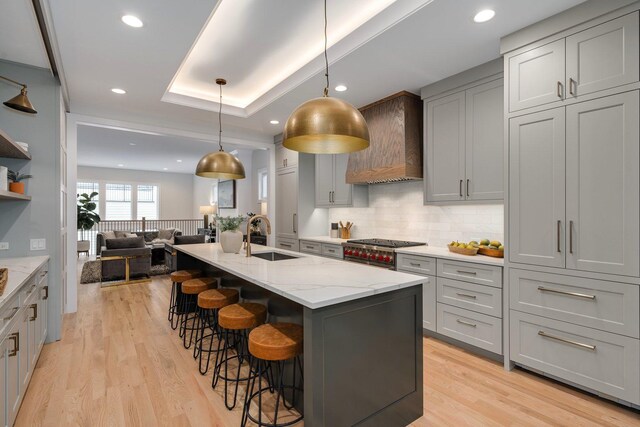 kitchen featuring hanging light fixtures, a breakfast bar, backsplash, and premium range hood