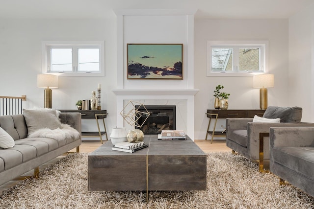 living room featuring a high end fireplace, plenty of natural light, and wood finished floors