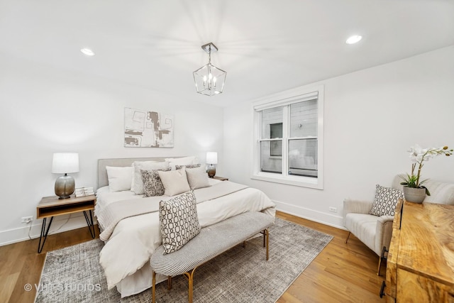 bedroom with light wood-type flooring and an inviting chandelier